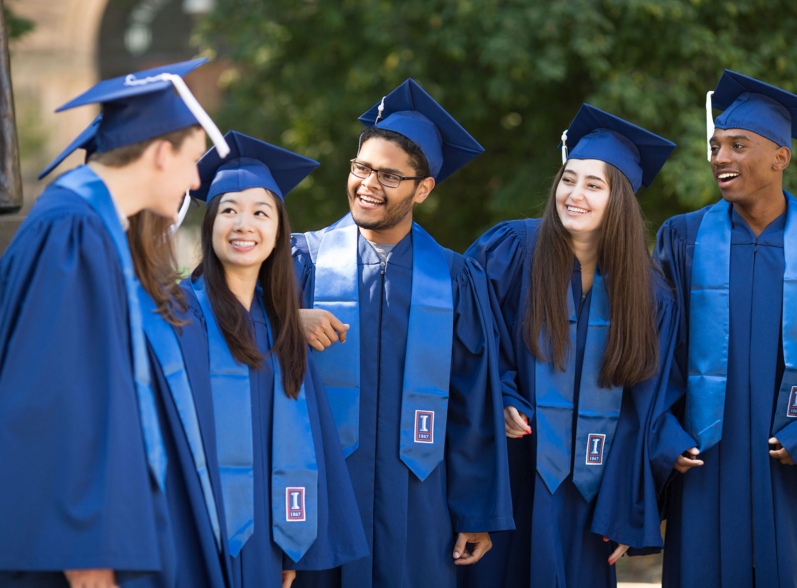 5 happy graduates in blue caps and gowns